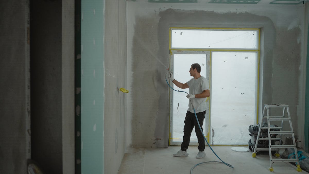Artisan peintre au pistolet airless lors d une renovation interieure