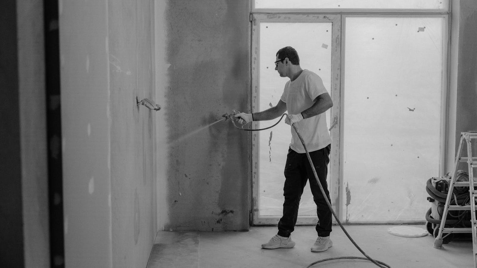 Peintre professionnel utilisant un pistolet airless sur un chantier de renovation