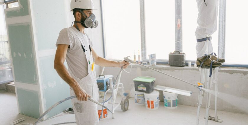 peintre professionnel utilisant un pistolet à peinture électrique airless sur chantier de rénovation