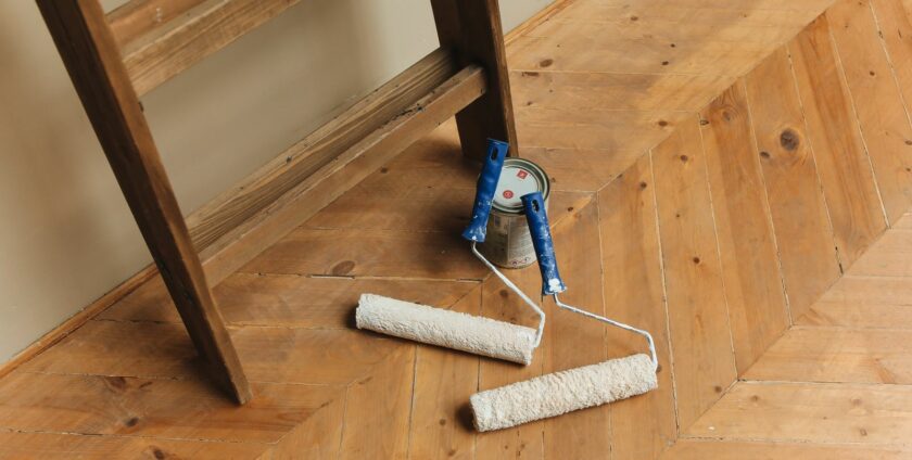 Rouleaux de peinture posés sur un parquet en bois point de Hongrie avant rénovation