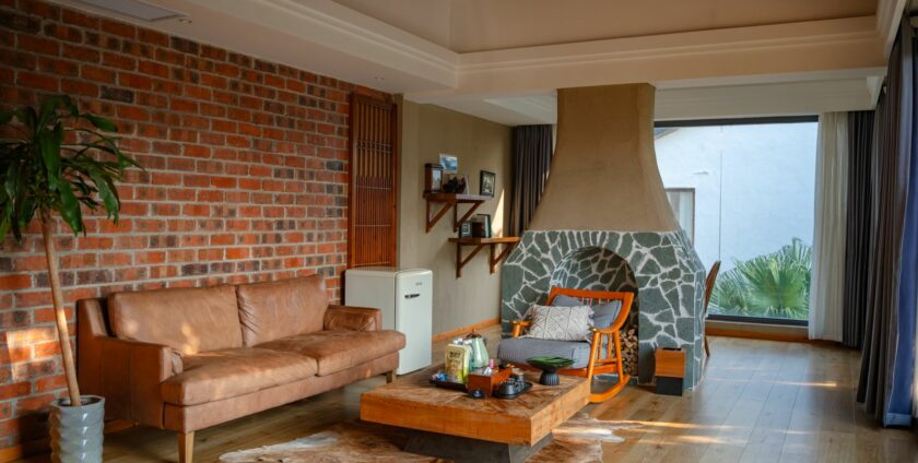 Salon chaleureux avec mur en briques, canapé cognac et mobilier en bois – tendances déco automne 2026