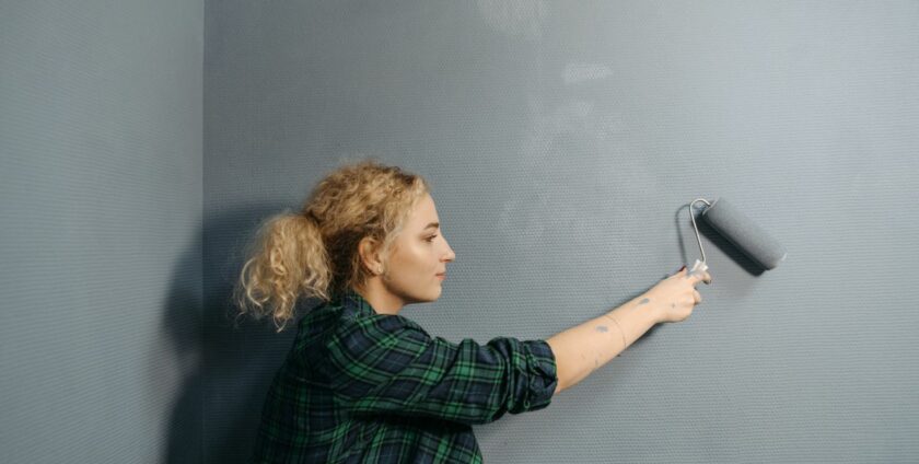 Peintre appliquant une finition satinée grise sur un mur intérieur avec un rouleau